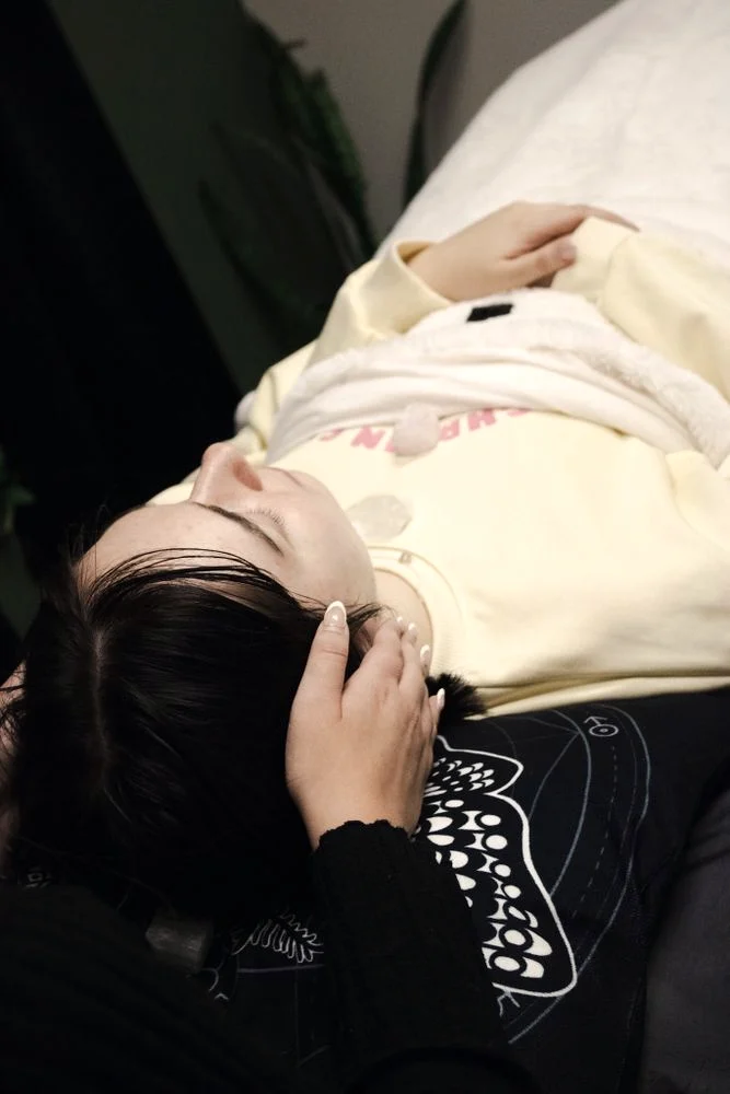 Hannah's hands resting at a client's head during a Reiki session